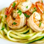 Close-up of a keto-friendly lemon butter garlic shrimp pasta with sautéed zucchini noodles, tender shrimp, and a rich golden butter sauce, garnished with parsley and black pepper.