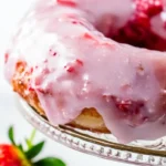 Close-up of a fluffy baked strawberry donut with fresh strawberry glaze dripping from the edges. A perfect sweet treat for brunch or dessert.