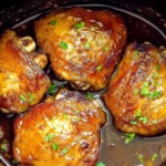Slow Cooker Brown Sugar Garlic Chicken thighs cooked in a rich, caramelized garlic and brown sugar sauce, garnished with fresh parsley inside a crockpot.