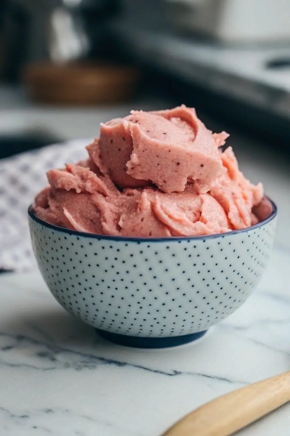 Soft pink dough for Strawberry Kiss Cookies in a patterned bowl, ready to be shaped into delicious, chocolate-filled treats.