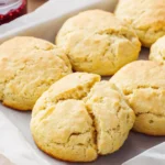 Freshly baked almond flour biscuits with golden tops on a parchment-lined tray, perfect for low-carb or keto brunch.