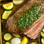 Juicy flank steak cooked to perfection, topped with fresh chimichurri sauce, and served with roasted zucchini, onions, and mushrooms on a golden sheet pan. A keto-friendly, low-carb, and Whole30-approved meal.