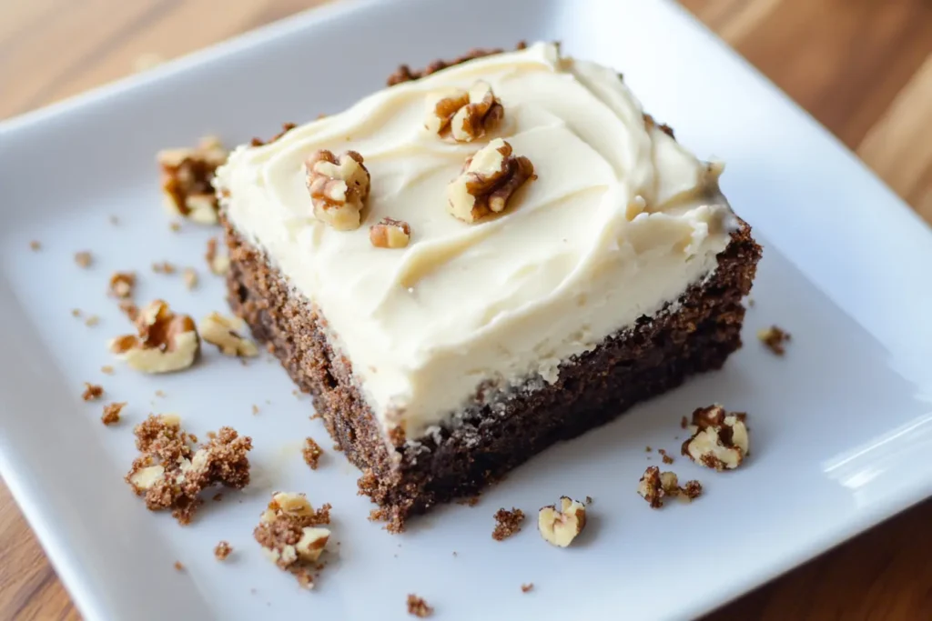 Keto banana bread brownie slice with creamy frosting and walnuts on a white plate