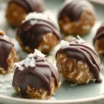Close-up of keto Scotcheroo Truffles with chocolate drizzle and coconut flakes on a ceramic plate