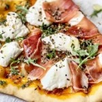 Close-up of a Prosciutto and Honey Burrata Pizza with crispy crust, creamy burrata, fresh arugula, and a drizzle of honey.