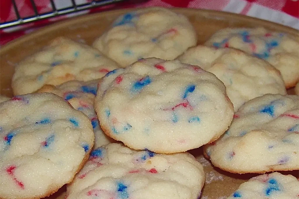 Soft-baked 4th of July cookies with red and blue sprinkles on a tan plate