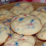 Soft-baked 4th of July cookies with red and blue sprinkles on a tan plate
