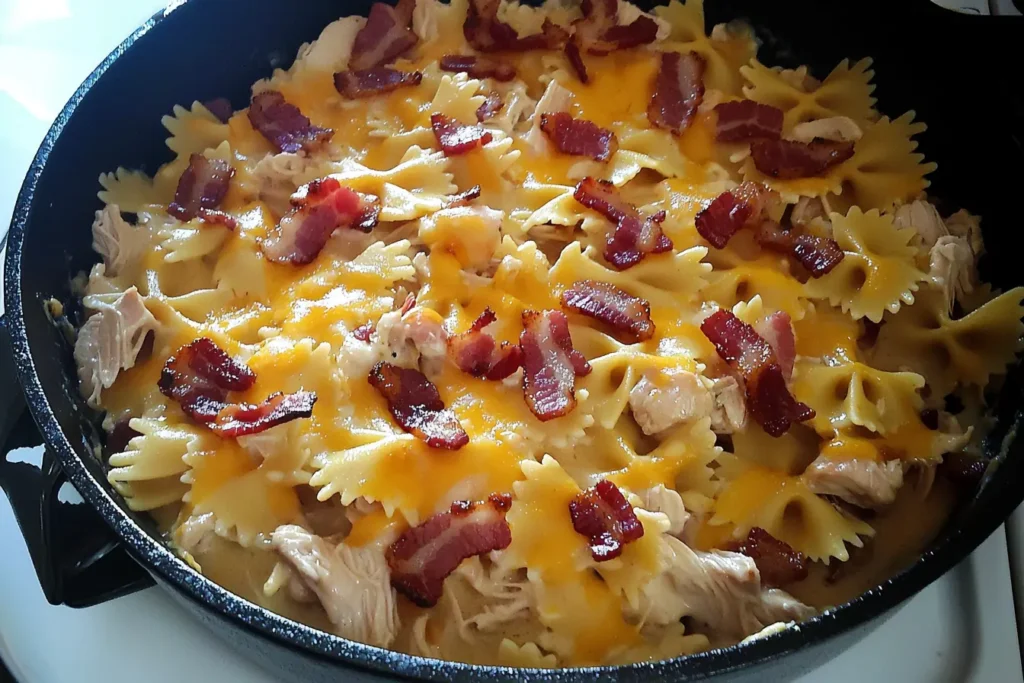 Creamy chicken bacon ranch pasta bake with melted cheese and crispy bacon in a cast iron skillet