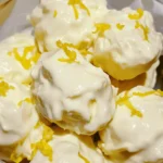 Close-up of creamy lemon bites in a glass bowl topped with fresh lemon zest, showcasing a smooth and rich texture.