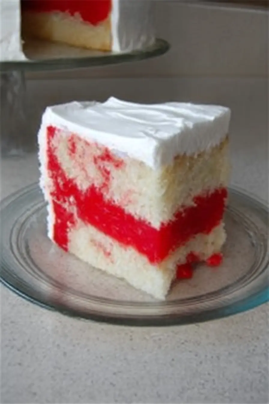 Layered Patriotic Poke Cake Slice with Whipped Topping Slice of patriotic poke cake with red gelatin layers and whipped topping