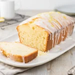 Freshly sliced lemon yogurt loaf with lemon glaze on white plate