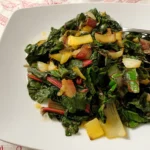 Sautéed rainbow chard with garlic, lemon, and caramelized stems served on a white plate