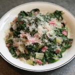 Sautéed Swiss chard with garlic, lemon, and melted Parmesan, served on a white plate