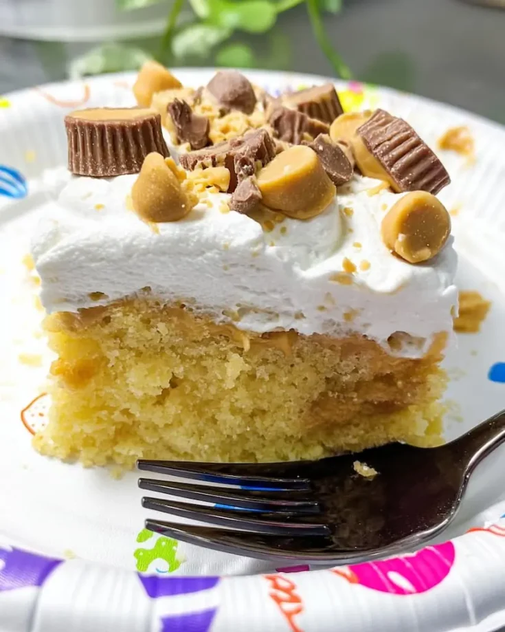 Slice of Better Than Anything peanut butter poke cake on a fork showing moist yellow cake with peanut butter filling and whipped topping with Reese's cups