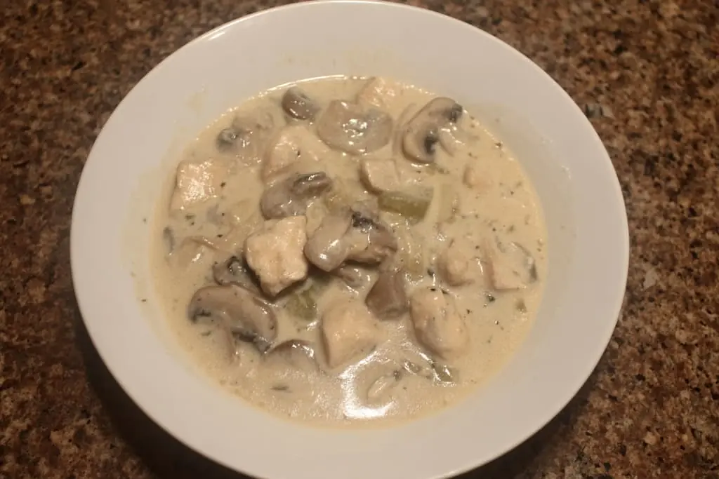 Bowl of creamy chicken and mushroom soup with tender chicken pieces and sliced mushrooms in rich cream sauce
