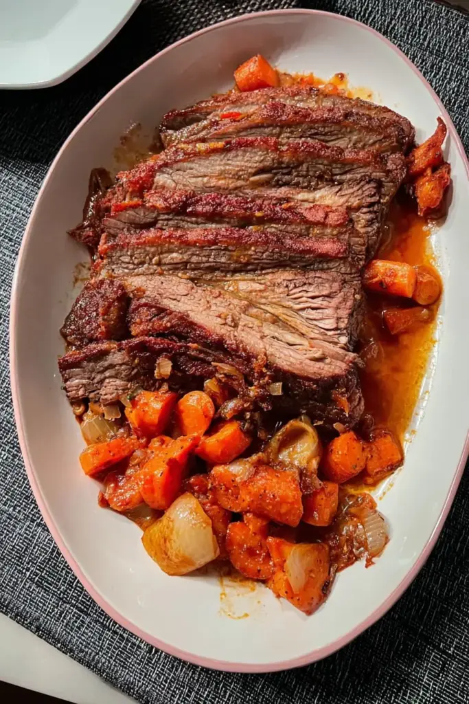 French onion brisket sliced against the grain on serving platter with tender carrots and rich sauce