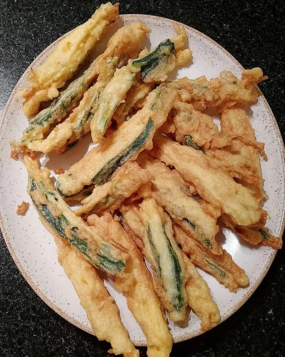 Plate of golden Parmesan-crusted zucchini fries freshly cooked in the air fryer.