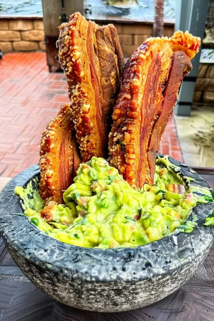 Homemade guacamole in stone molcajete with beef jerky strips for keto high-protein snacking