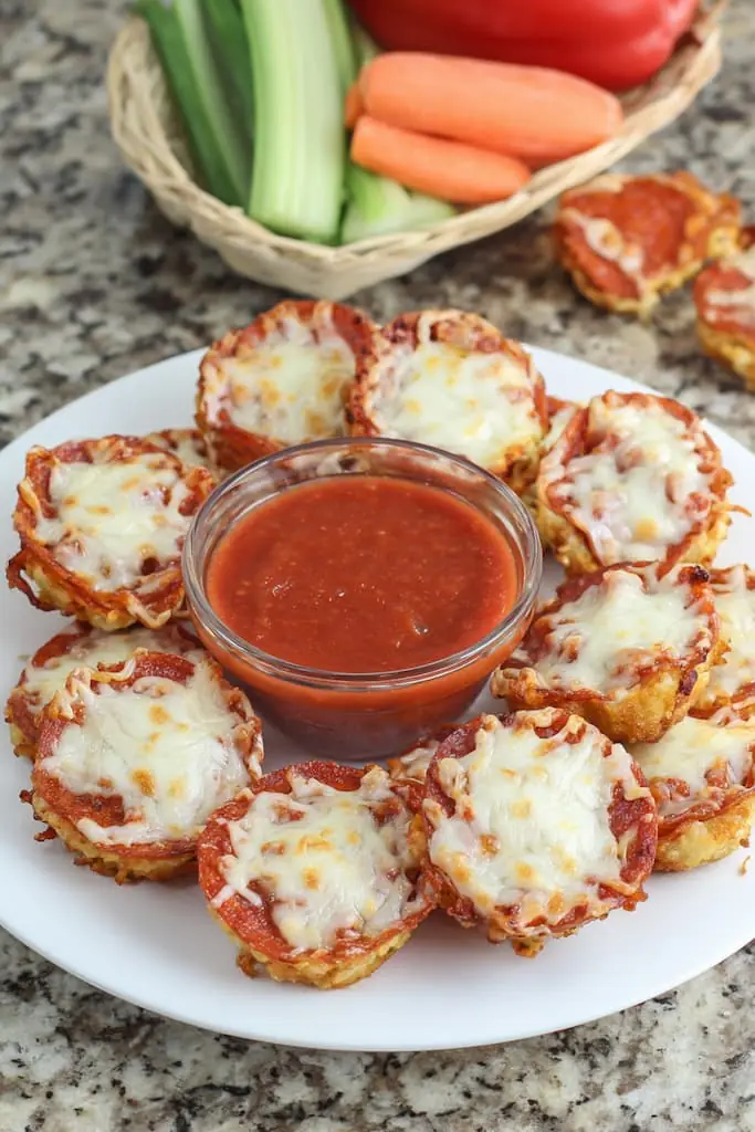 Keto pepperoni pizza bites with melted mozzarella cheese and marinara dipping sauce on white plate