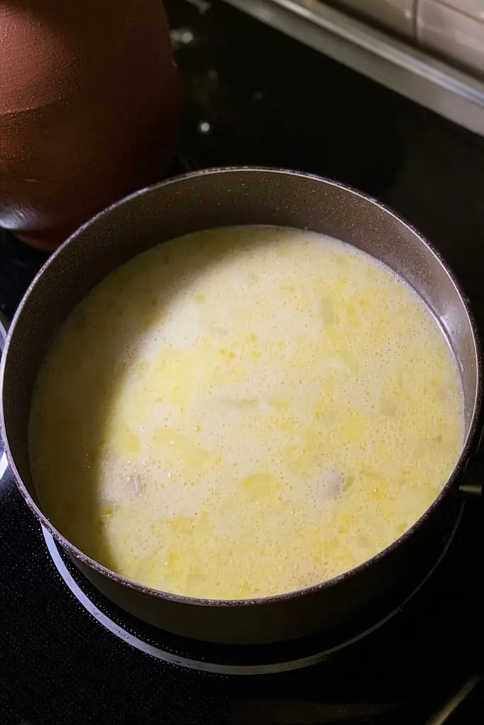 Creamy potato leek soup simmering in large stainless steel pot on stovetop before final blending