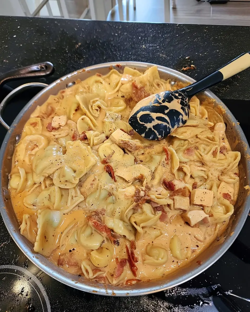 Creamy marry me chicken tortellini tossed with bacon, sundried tomatoes, and Parmesan in a stainless-steel skillet.
