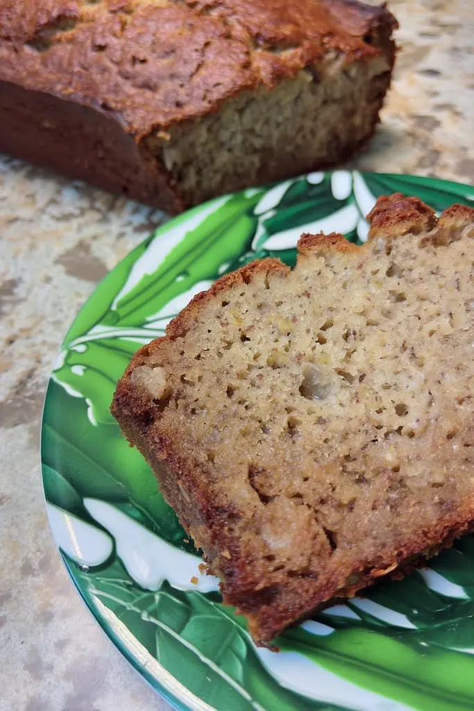Close up view of moist banana bread slice showing tender crumb texture on green leaf plate
